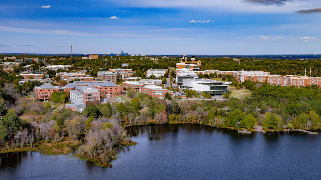 Aerial view of Lake Raleigh and Centennial Campus with blue sky and scattered white clouds in distance.
