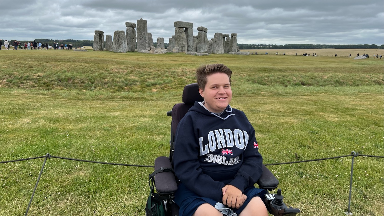 Jack Bolton poses for a photo wearing a dark blue sweatshirt. The ruins of Stonehenge are in the background.