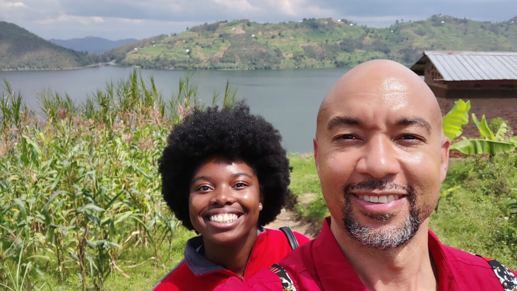 Jenni Mangala, left, and Kanton Reynolds, right, pose for a selfie with a building, lake and mountains in the background.
