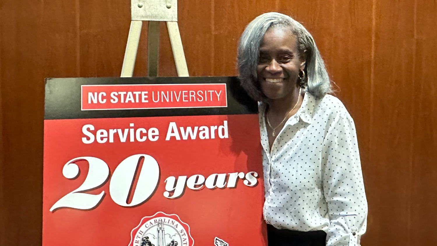 A picture of Tracy Brown in front of sign for the Service Awards.