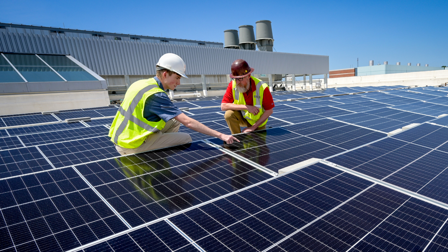 Student and staff examine solar array on top of Fitts-Woolard Hall wearing PPE.