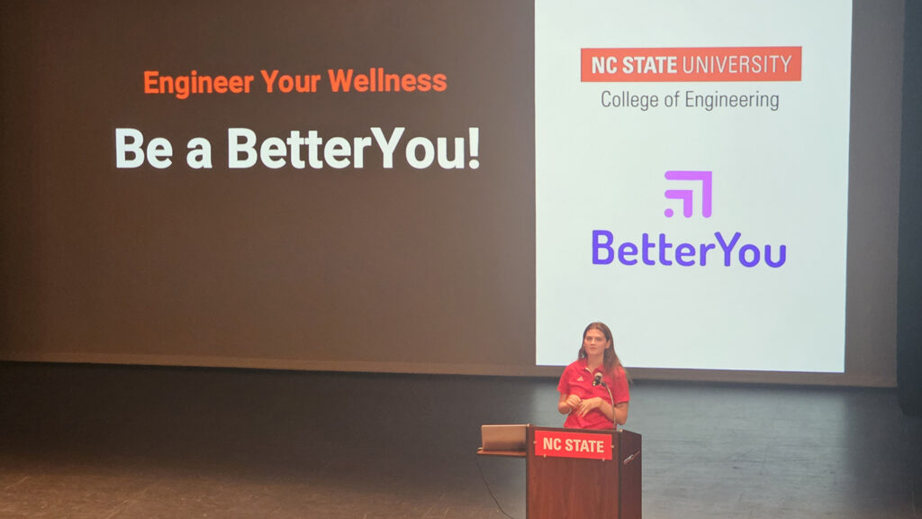 Shannon Dupree on stage behind lecturn while presenting the E-Well program at NC State University.