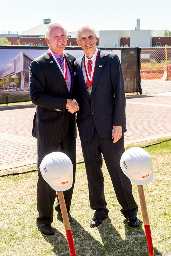 Ed Fitts, left, and Ed Woolard, right, shake hands at the groundbreaking for Fitts-Woolard Hall.