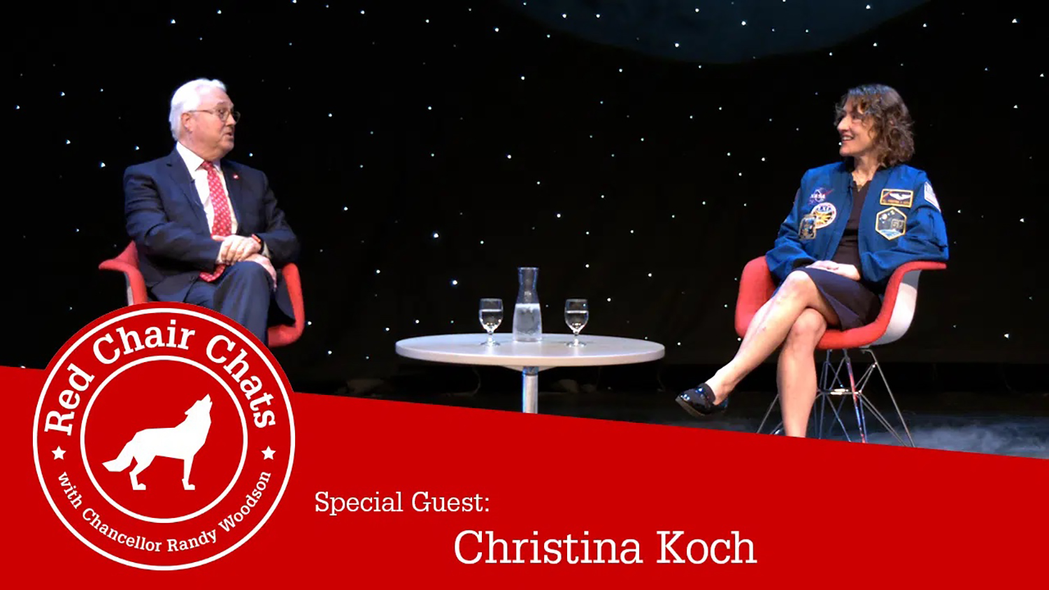 Alumna Christina Koch, right, speaks with Chancellor Randy Woodson during a recent Red Chair Chats podcast. A red banner runs across the bottom of the image with the NC State wolf silhouette on the left.