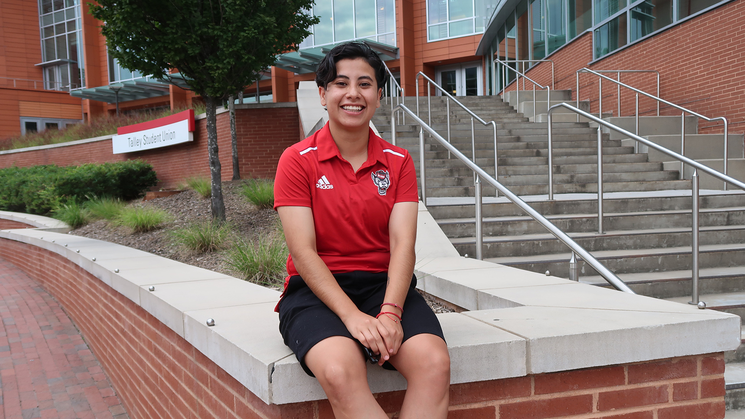 Daisy Aguilar Aguilar poses for a picture sitting next to the stairs at Talley Student Union.