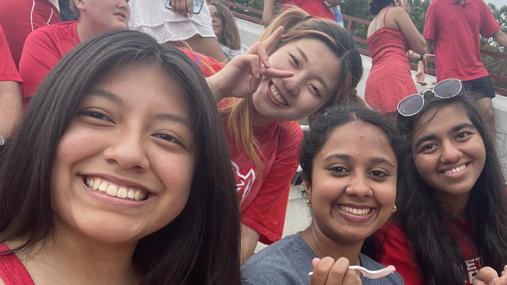 Amyy Deepee, right, smiles for a photo with three friends during an NC State football game.
