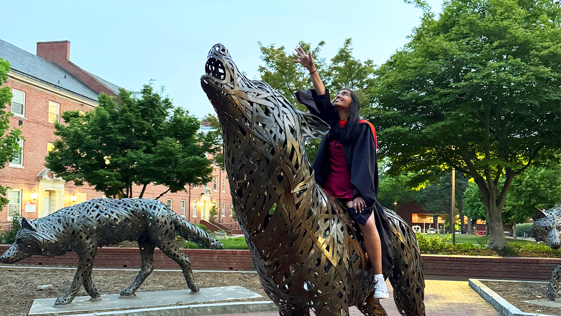 Amy Deepee sits atop one of the bronze wolves at NC State University.