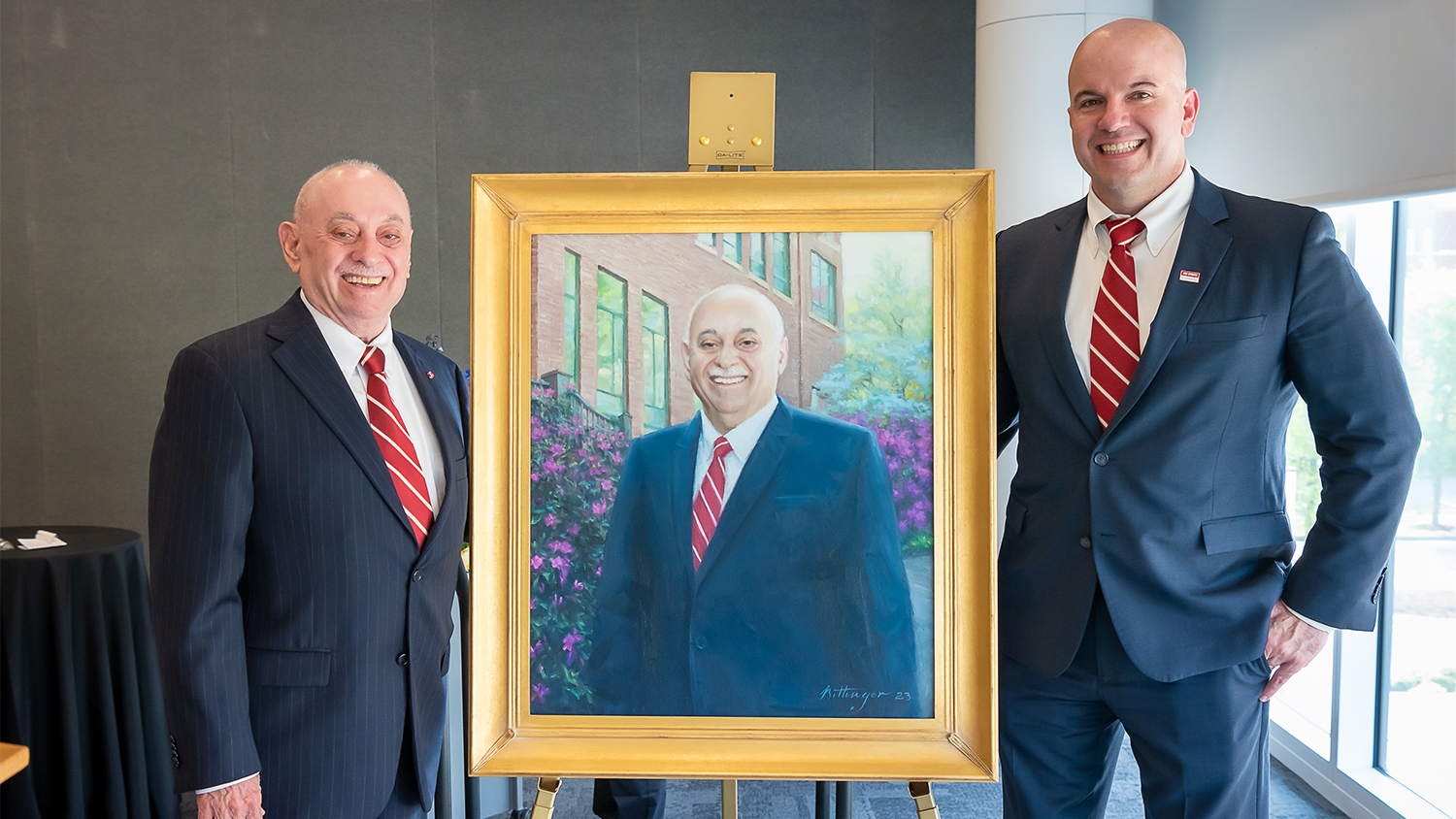 Former dean Louis Martin-Vega, left, and current dean Jim Pfaendtner, right, flank the newly revealed painted portrait of Louis-Martin Vega.