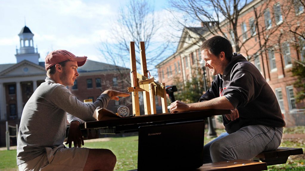 Engineering students collaborate on a projectile launcher in the courtyard of the Honors Village.