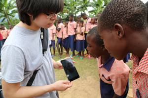 Daniel Bun shows picture from reading on tablet to students at Nkumba Primary School 