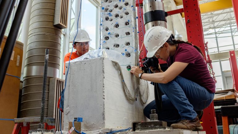 Ph.D. student Gabby Haro (right) and undergraduate research assistant Luis Angel (left) examining a concrete wall section after a simulated earthquake at the Constructed Facilities Lab on Centennial Campus.